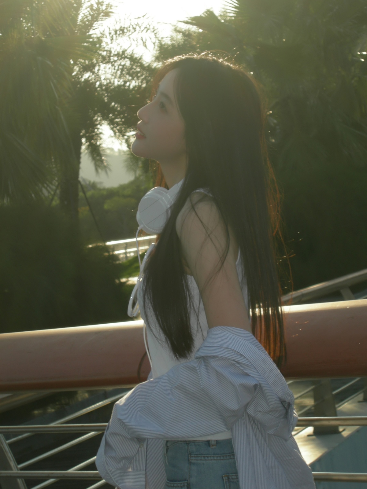 一位穿着白色衬衫的年轻女子站在一座桥上