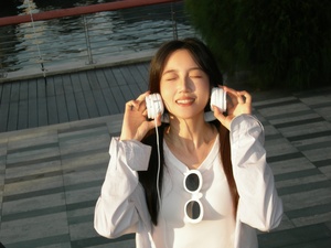 一个年轻女子穿着白色衬衫 戴着耳机在打电话。