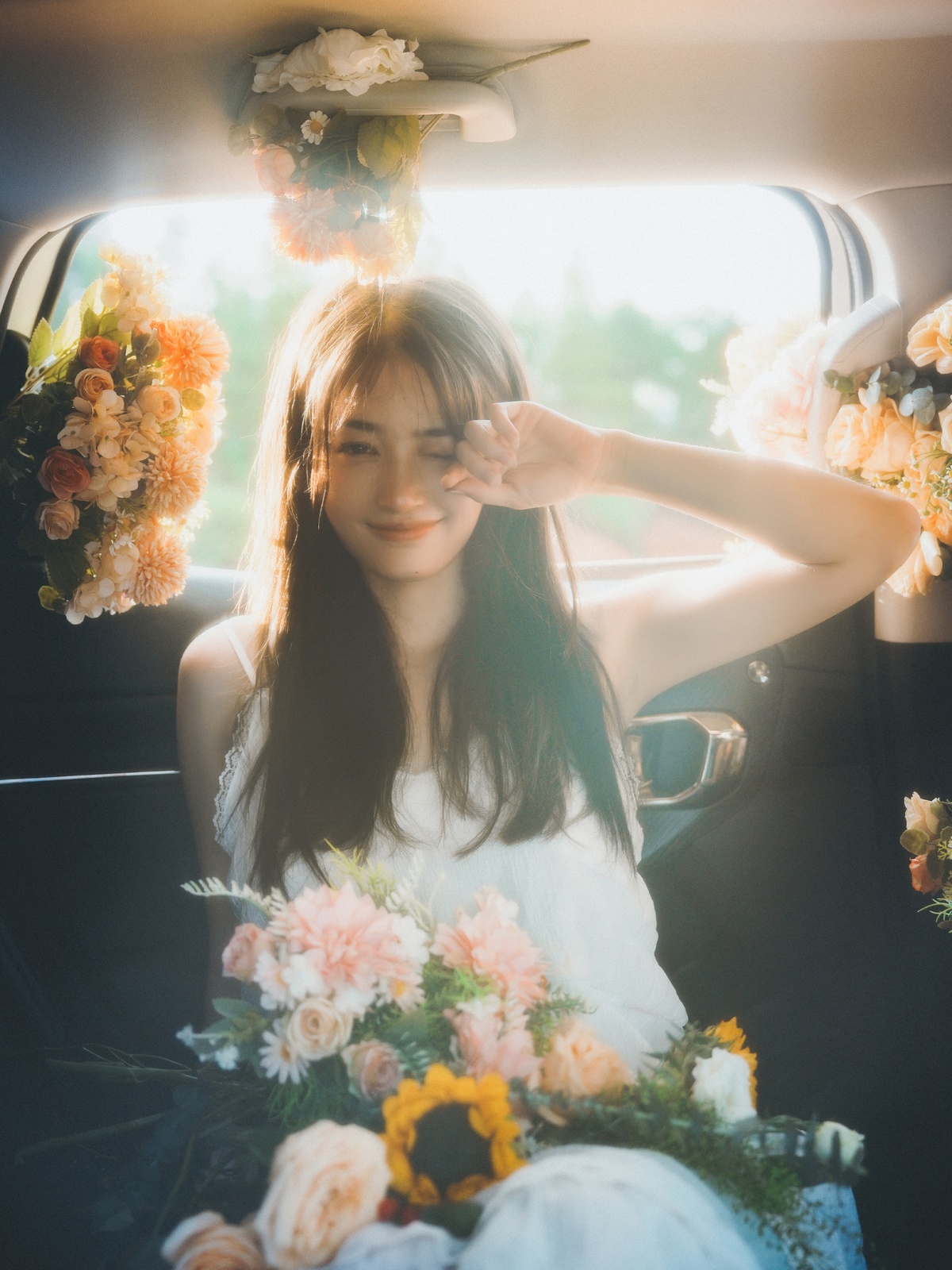 一位坐在汽车里的女人 周围有花。