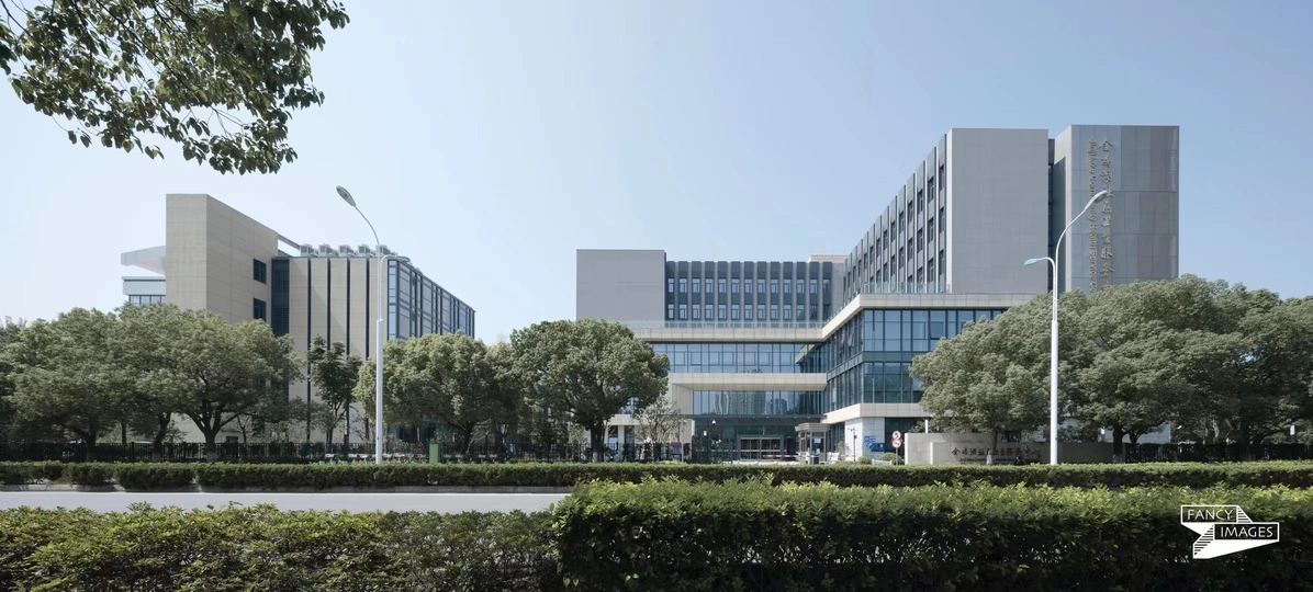 树荫下的公园 前面有一张长椅 旁边有一座大型建筑。