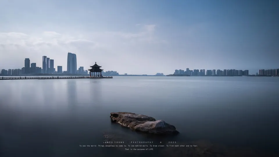 前景有岩石的大型水面 远处有城市的天际线