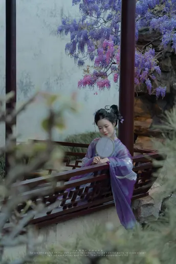 一位穿着和服的年轻女子站在一座有紫花建筑前