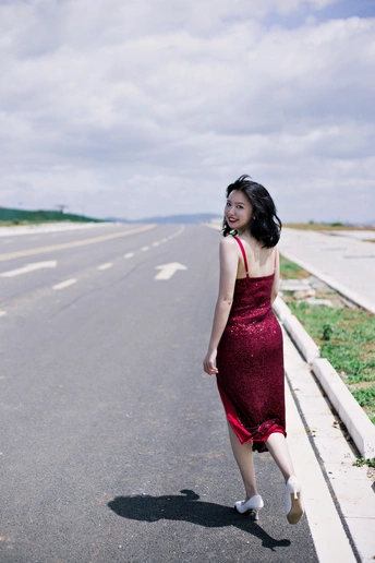 一个穿着红色连衣裙的年轻女子走在一条空荡荡的路上