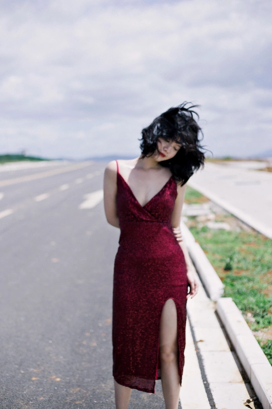 一个穿着红色连衣裙的女人走在一条空荡荡的路上