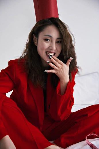 一位穿着红帽和裙子 抽烟的女人坐在床上