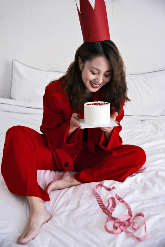 一位穿着红色衣服的女人坐在床上 手里拿着一杯咖啡。