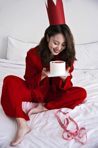 一位穿着红色衣服的女人坐在床上 手里拿着一杯咖啡。