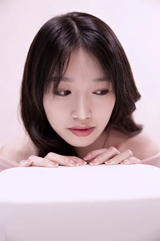 一位年轻女子坐在白色笔记本电脑前 脸上带着惊讶的表情。