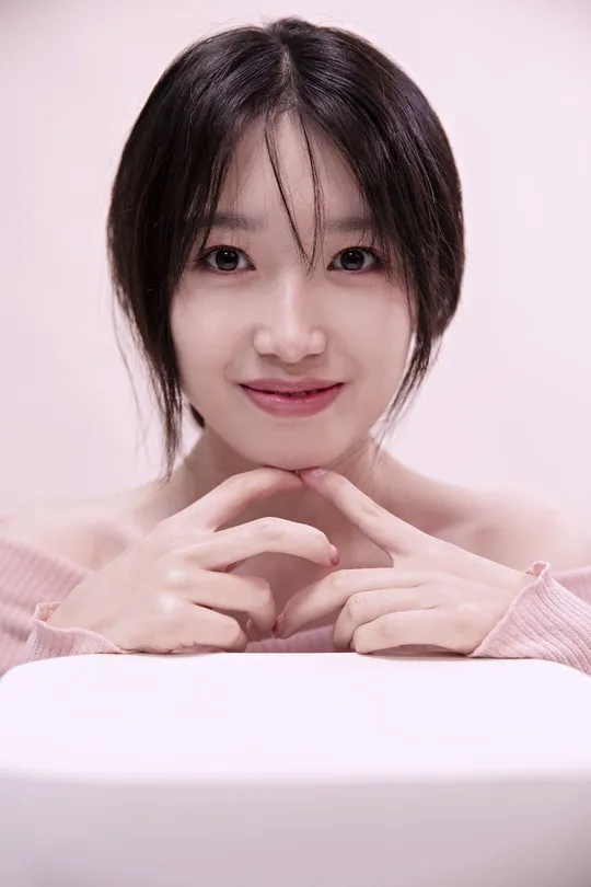 一个留着短发的年轻女子坐在一张白色桌子旁 双手托下巴