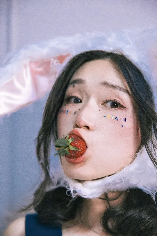 一位穿着红色口红的女青年 唇上带着草莓。