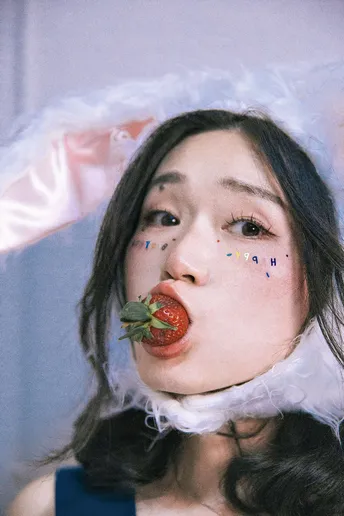 一位穿着红色口红的女青年 唇上带着草莓。