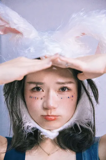 一个戴着手套的女孩脸上化了妆 头戴一顶帽子。