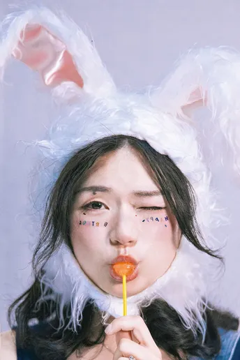 一个小女孩穿着兔子服装 嘴里咬着胡萝卜。