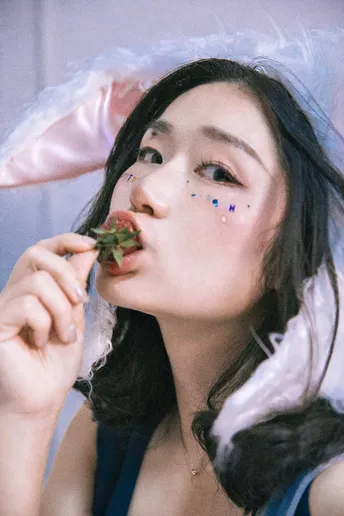 一位戴帽子穿裙子的年轻女子正在吃草莓。