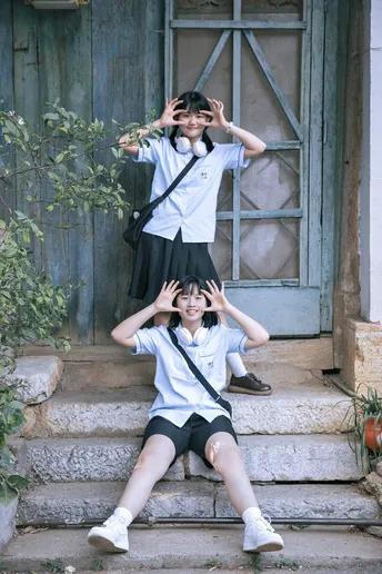 一个穿着制服的年轻男孩和女孩坐在房子外面的台阶上