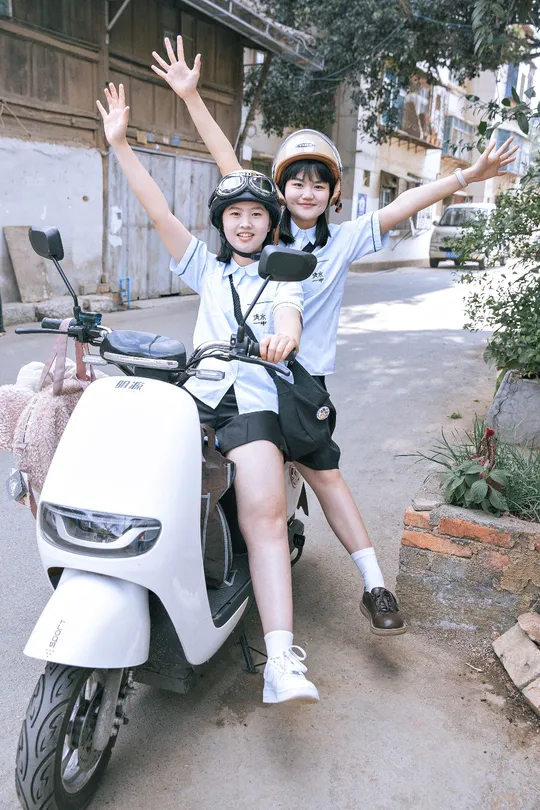 一些人在骑摩托车或滑板车 一个男孩和一个女孩 微笑着戴着头盔。