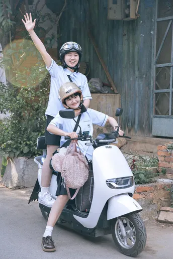 一个戴头盔的男女骑着摩托车 带着一个年轻男孩和一个女孩骑着滑板车。