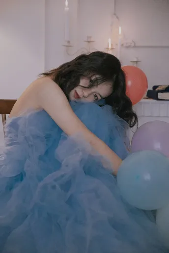 一位穿着蓝色连衣裙的年轻女子被气球包围着。