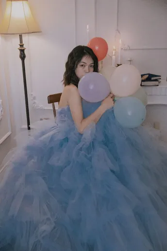 一位穿着蓝色裙子的女士拿着一束气球