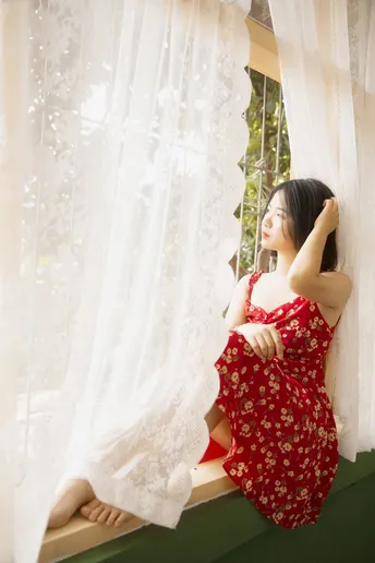 一位穿着红裙子的年轻女子正在窗口向外看