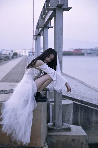 一个穿着白色裙子的美女坐在码头上
