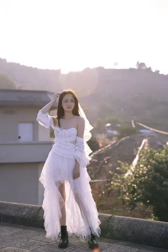 一位穿着白色连衣裙站在屋顶上的女人