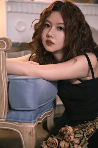 一位美丽的红发年轻女子穿着黑色连衣裙坐在蓝色椅子上