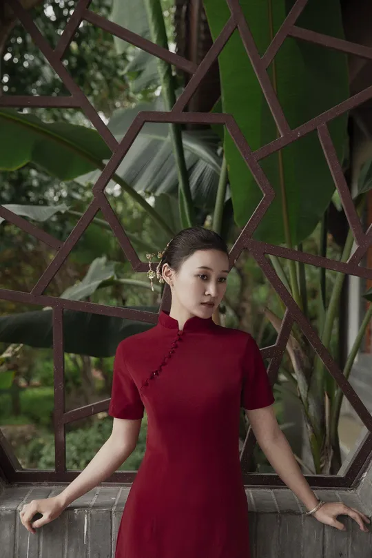 一位穿着红色连衣裙的女人站在一棵榕树前