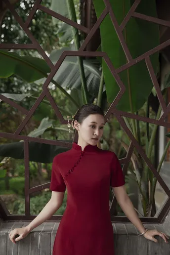 一位穿着红色连衣裙的女人站在一棵榕树前