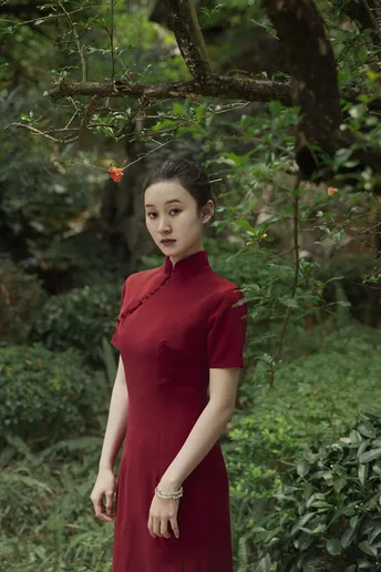 一位穿着红裙子的年轻女子站在森林中