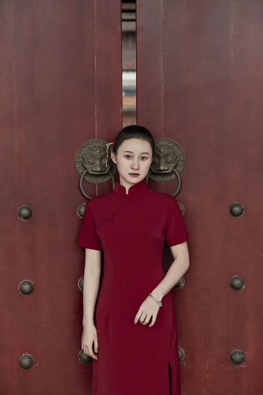 一位穿着红裙子的年轻女子站在门前