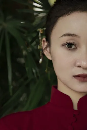 一位穿着红衬衫和耳环的女性在植物前为肖像摆姿势