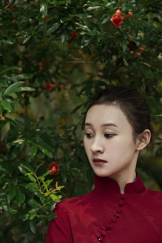 一位穿着红衬衫站在一棵树前有花的女士