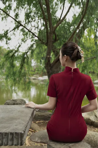 一位年轻女子坐在湖或河岸前的岩石上