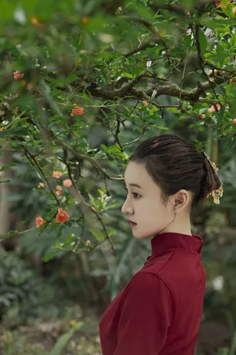 一位穿着红裙子的年轻女子站在一棵树下