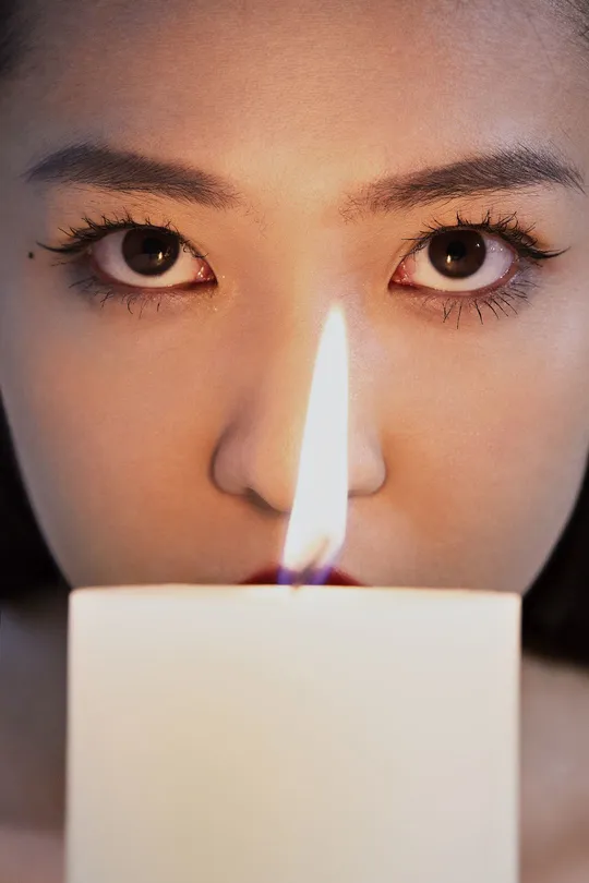 一位年轻女子举着一支点燃的蜡烛对着她的脸