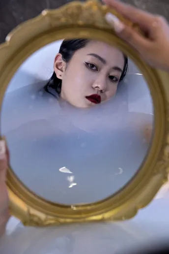 一位女士脸上涂着口红对着镜子