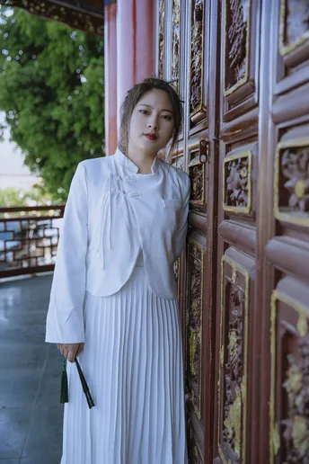 一位穿着传统白色长裙的年轻女子站在寺庙门前