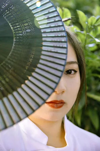 一个戴白色帽子 举着伞遮住脸的女人