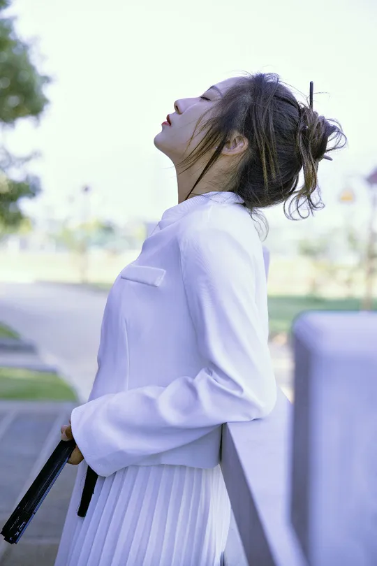 一位穿着白色连衣裙的年轻女子拿着雨伞