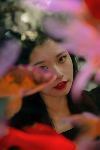 一位年轻女子在她的面前有一束红色的花在镜子中反射。