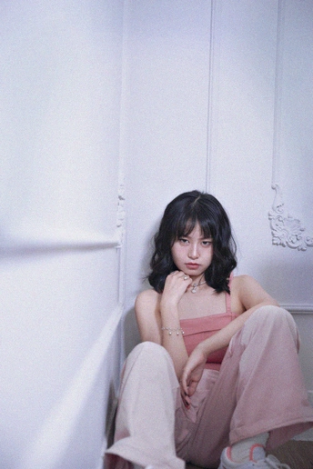 一位年轻女子坐在地板上 靠在一面白色墙壁上