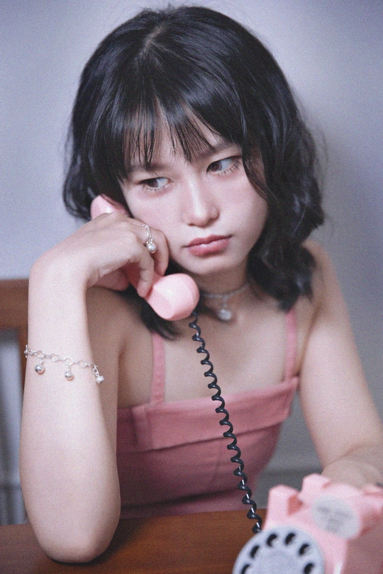 一个穿着粉红色连衣裙的年轻女子坐在桌子旁打电话