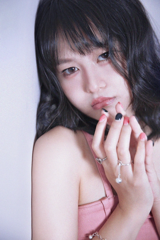 一个穿着粉红色裙子的年轻女子手里拿着香烟 手指上戴着戒指。