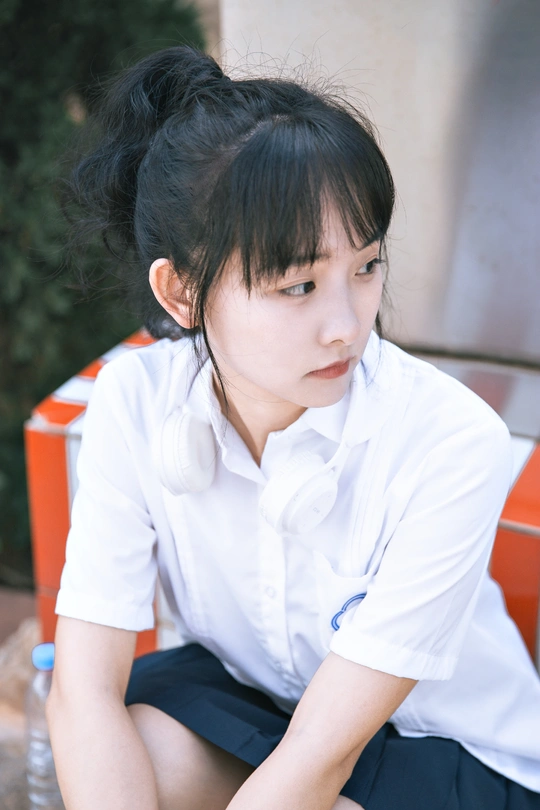 一个穿着白衬衫的年轻女孩坐在长凳上