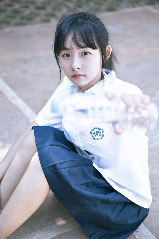 一个小女孩穿着制服坐在长凳上