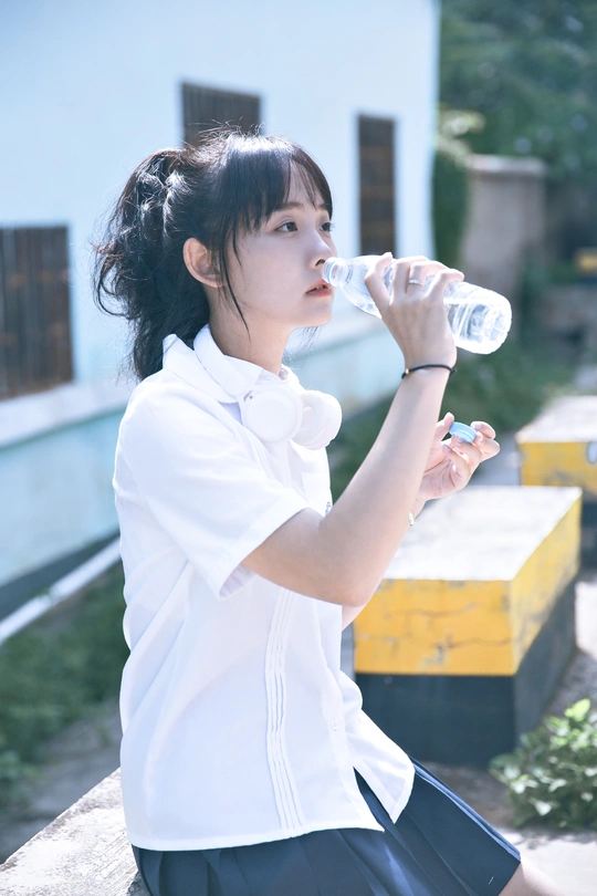 一个穿着白色校服的年轻女子拿着一瓶水