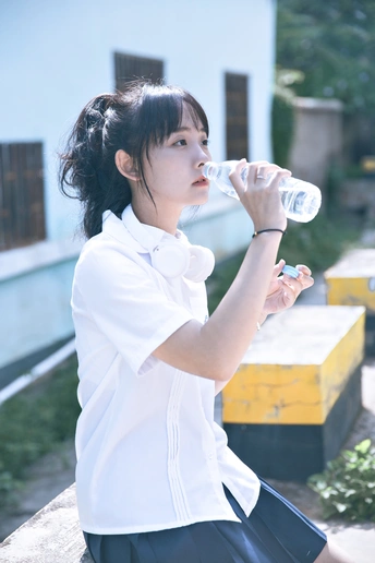 一个穿着白色校服的年轻女子拿着一瓶水