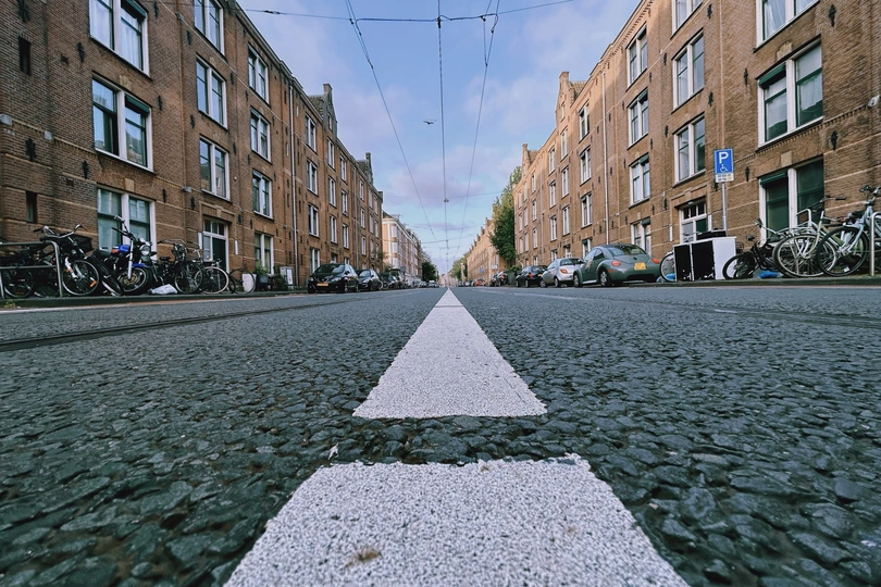 摩托车停在路边的一条城市街道上 右侧有一个指向右的白箭头。