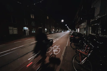 夜晚的黑暗城市街道 人们骑着自行车在道路上行驶 路边的建筑物。